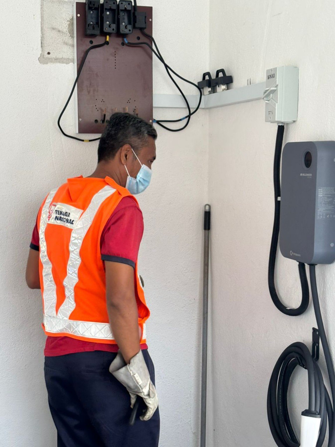 Site inspection beside installed EV wallbox, with a worker in safety vest